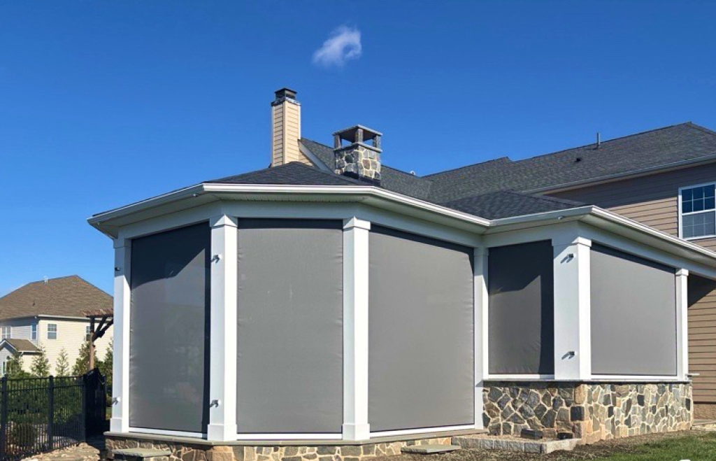Custom MagnaTrack retractable screen system on octagonal porch enclosure with white trim and stone base, Montgomery County PA—M.C. Weeks, Inc.