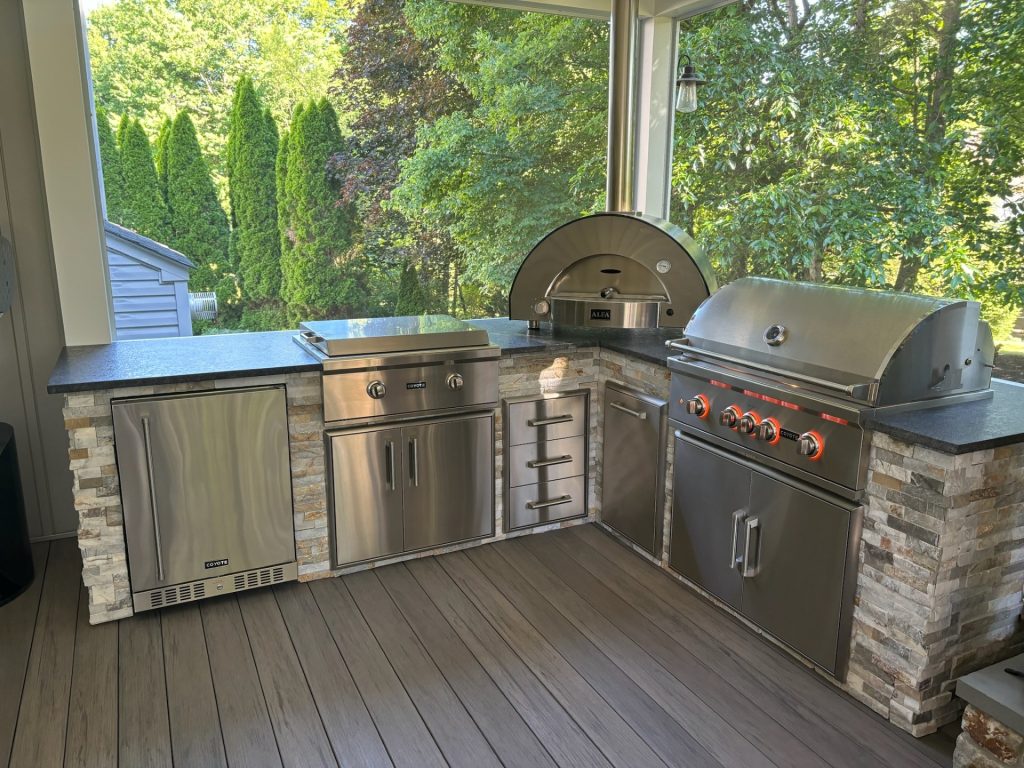 Custom outdoor kitchen with Coyote grill, Alfa pizza oven, and stainless cabinetry on a covered deck installed by M.C. Weeks, Inc. in greater Philadelphia PA